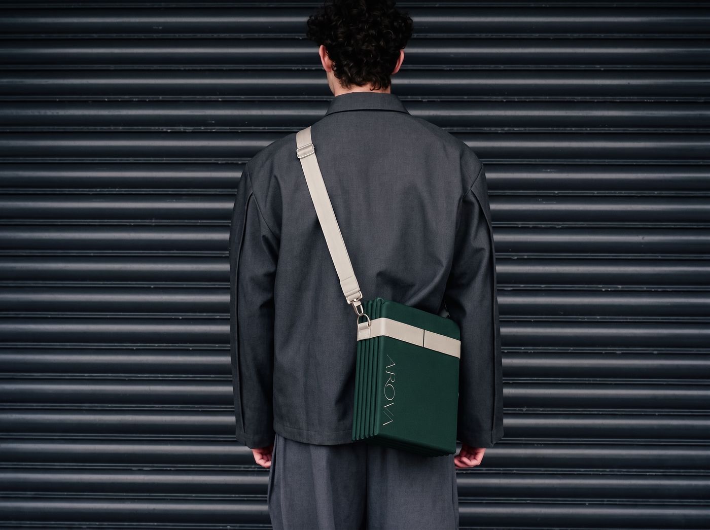 A man from behind wearing the folded AROVA mat on a strap