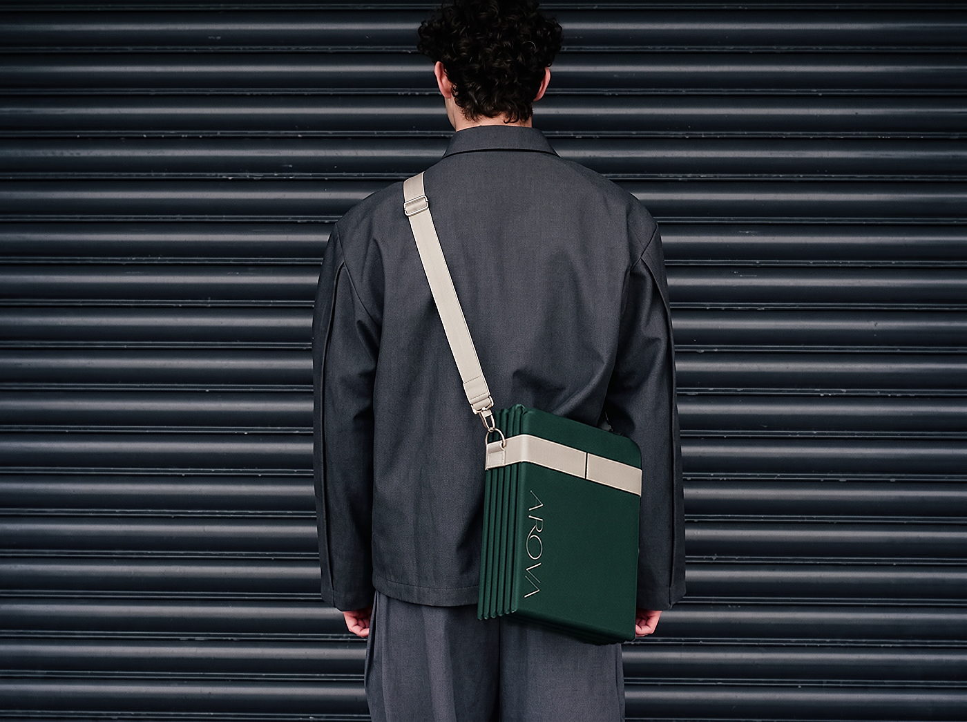 A man from behind wearing the folded AROVA mat on a strap