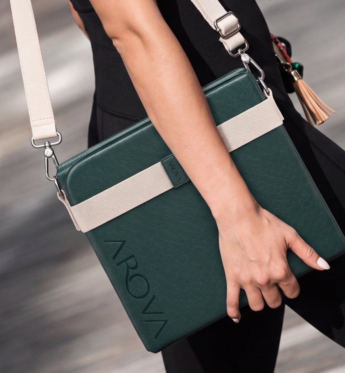 A woman carrying the folded AROVA mat by hand, its strap over her shoulder