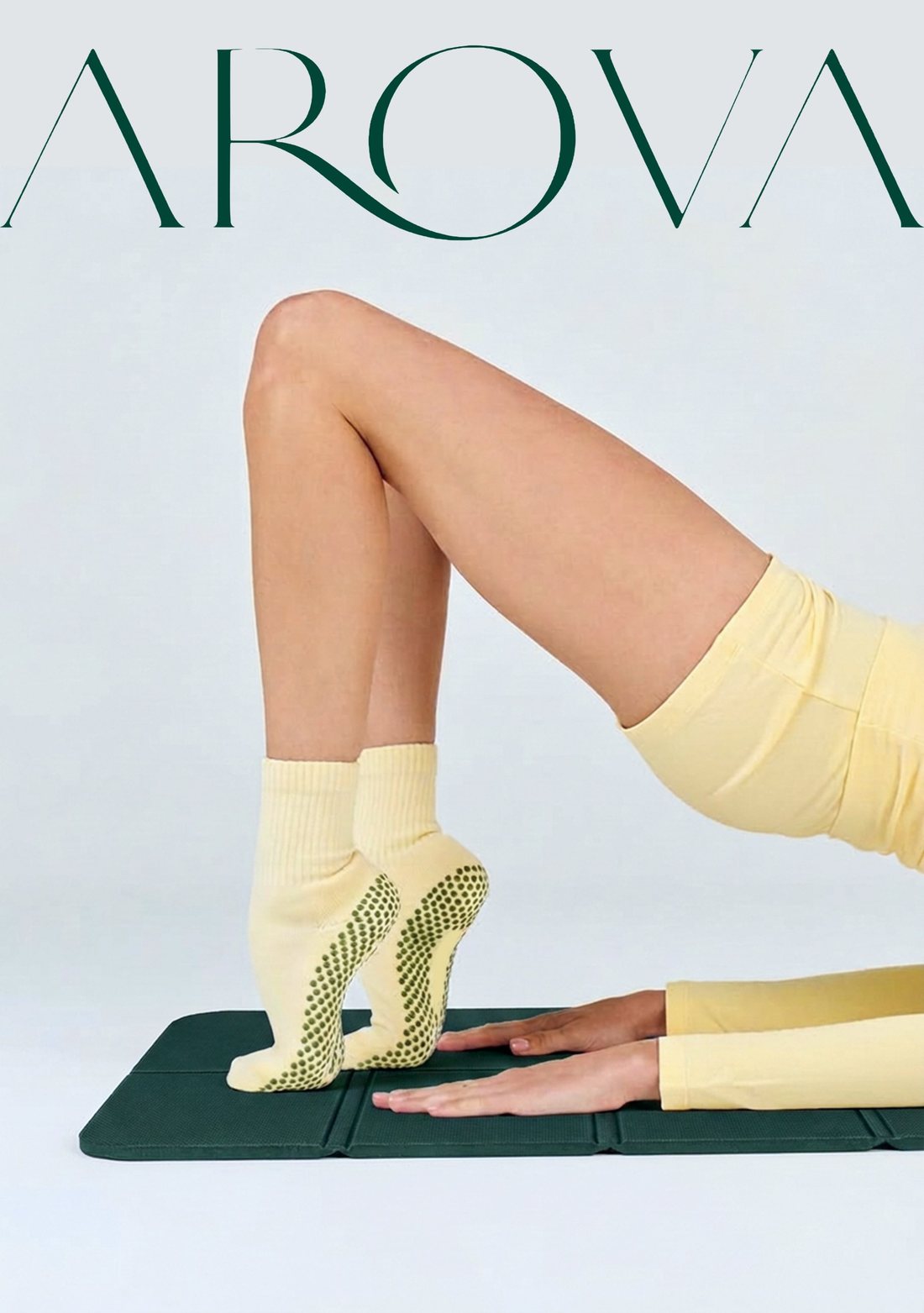 Legs in yellow grip socks rising into a pose on the AROVA mat, under the AROVA wordmark